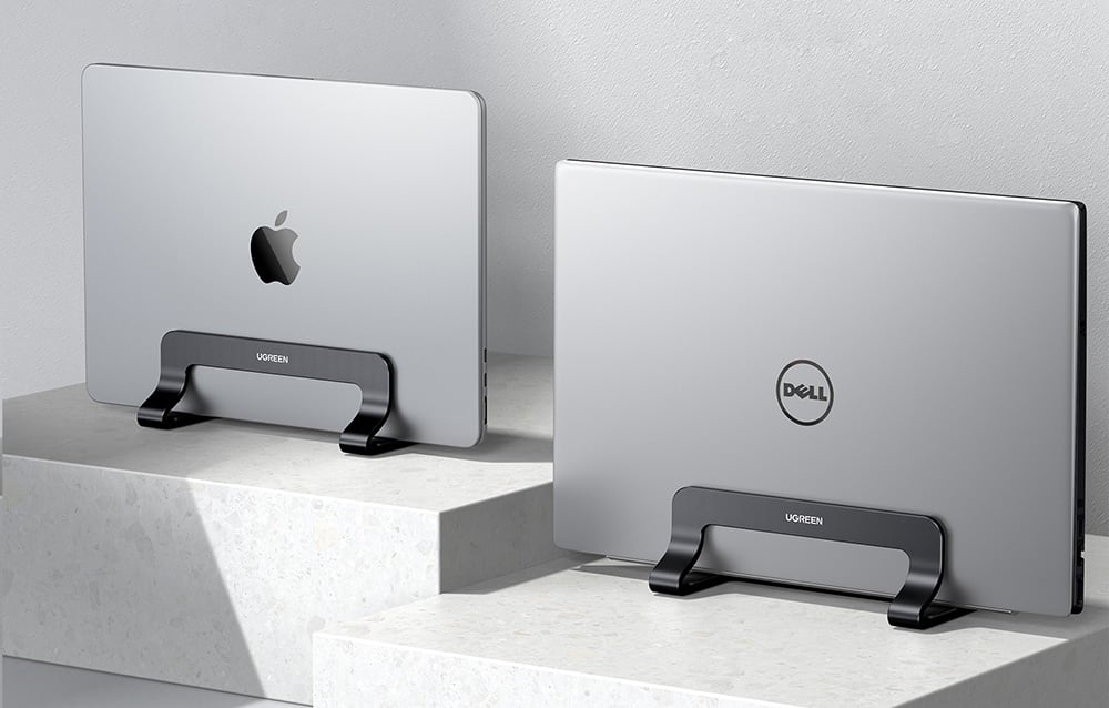 Dwa laptopy - MacBook i Dell - w czarnych podstawkach na białych półkach