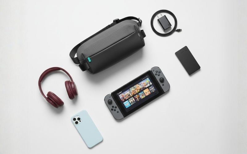 Szara torba YAXO na konsolę leży obok Nintendo Switcha, słuchawek, telefonu, powerbanku i kabla.